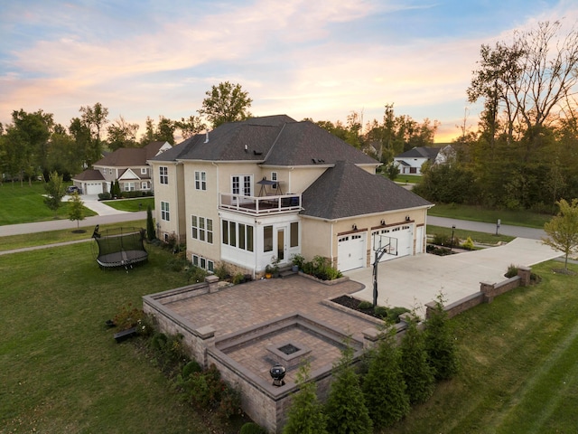 back house at dusk featuring a yard and a balcony