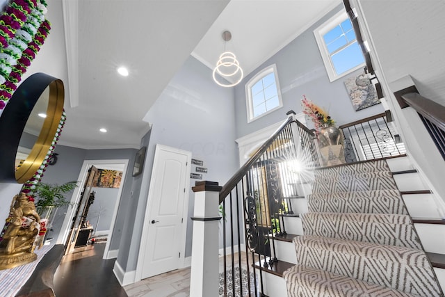 stairway with a towering ceiling, hardwood / wood-style flooring, and crown molding