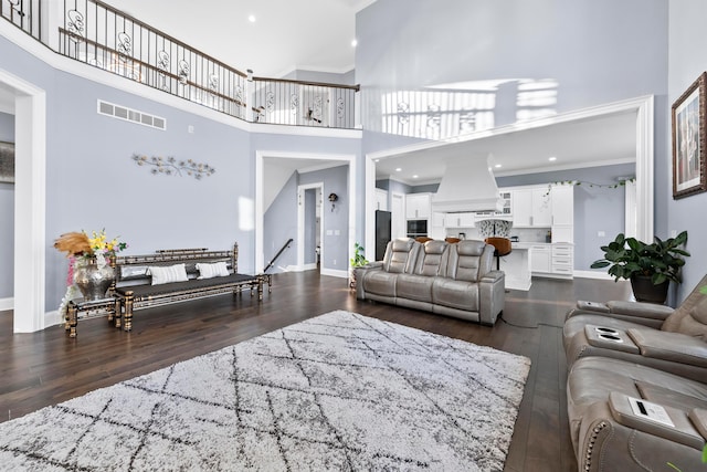 living room featuring dark hardwood / wood-style floors, a towering ceiling, and crown molding