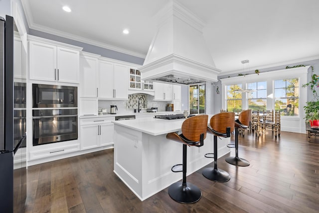 kitchen featuring dark wood-type flooring, white cabinets, appliances with stainless steel finishes, a kitchen island, and custom range hood