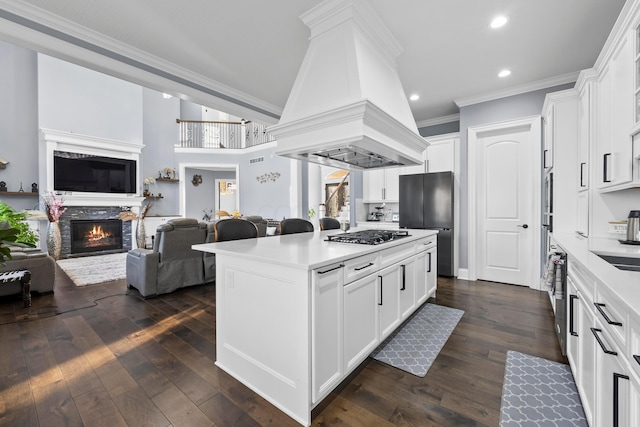 kitchen featuring premium range hood, a fireplace, white cabinetry, and dark hardwood / wood-style flooring