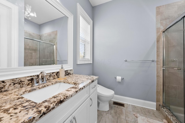 bathroom featuring vanity, toilet, and a shower with shower door