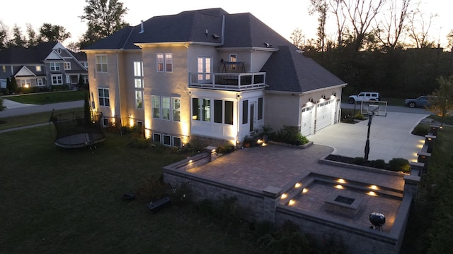 back house at dusk with a balcony and a garage