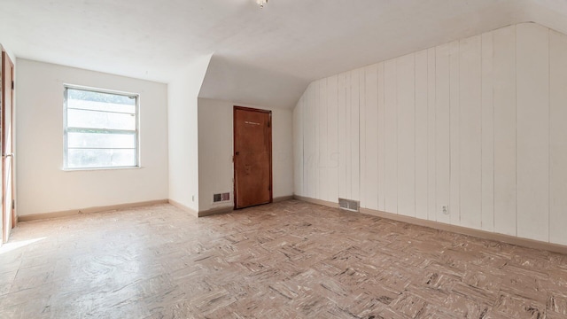 unfurnished room with vaulted ceiling and wood walls