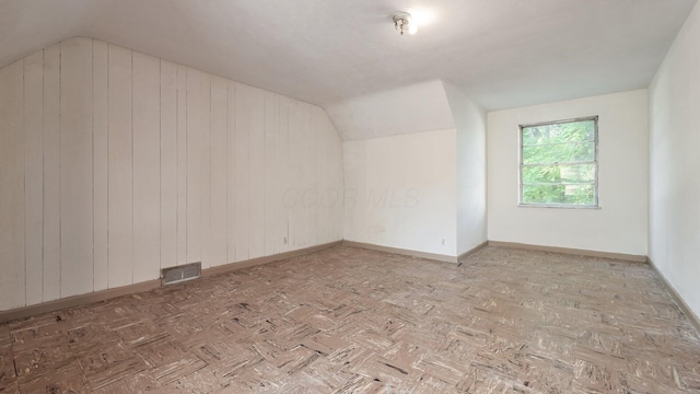 additional living space with wood walls and lofted ceiling