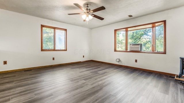 unfurnished room with a textured ceiling, ceiling fan, dark wood-type flooring, and a wealth of natural light