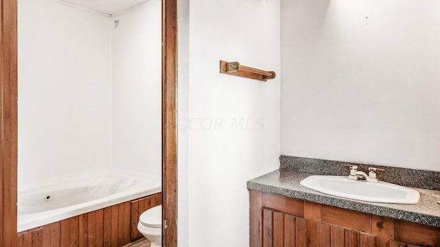 bathroom with a washtub, toilet, and vanity