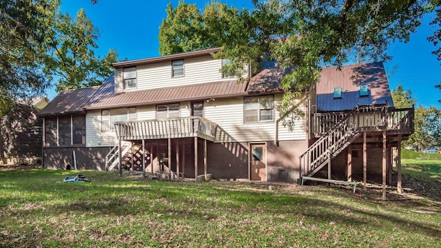 rear view of property featuring a yard, a sunroom, and a wooden deck