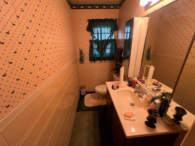 bathroom with vanity, toilet, and tile walls