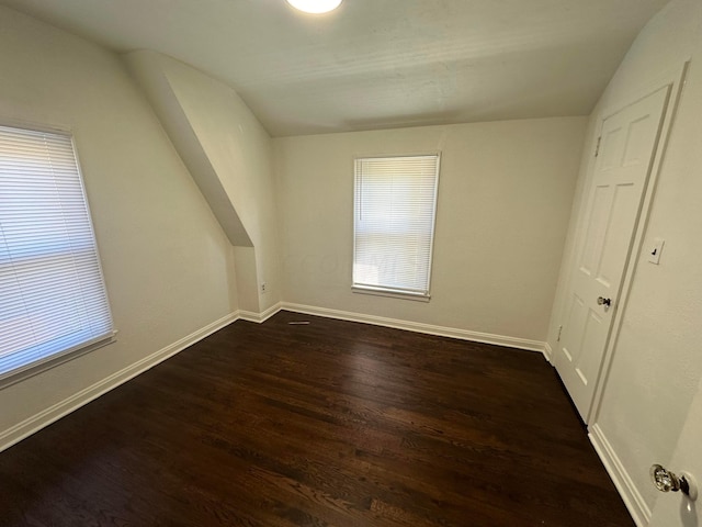 additional living space featuring dark wood-type flooring and vaulted ceiling