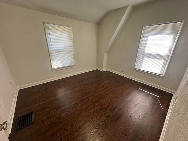 unfurnished room featuring lofted ceiling and dark hardwood / wood-style floors