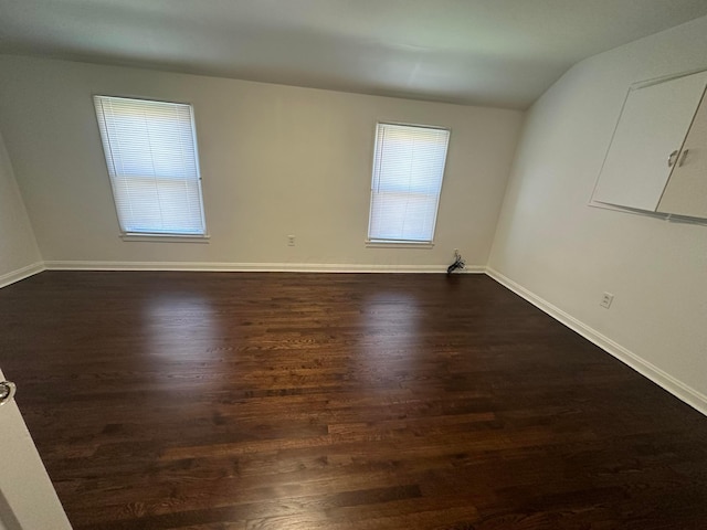 empty room featuring dark wood-type flooring and vaulted ceiling