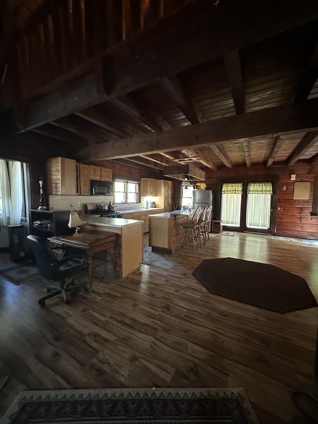 kitchen featuring beam ceiling, hardwood / wood-style flooring, plenty of natural light, and wood walls