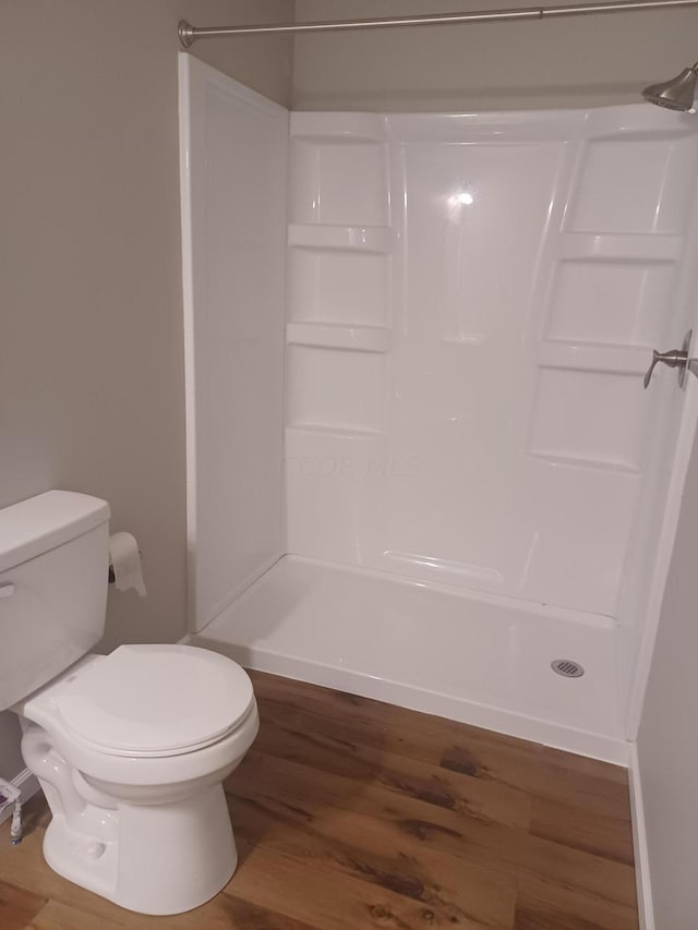 bathroom featuring toilet, wood-type flooring, and walk in shower