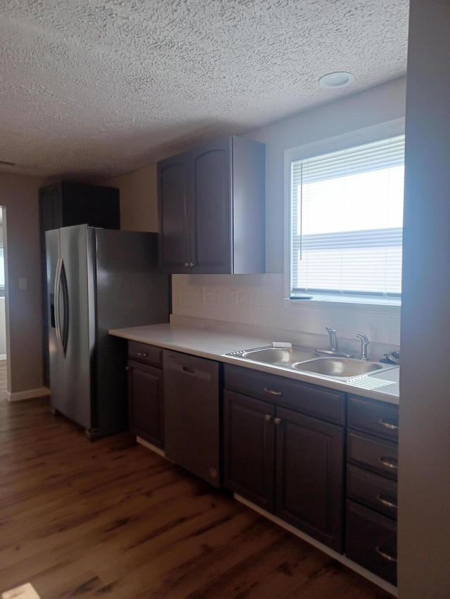 kitchen featuring dark brown cabinets, sink, stainless steel appliances, and dark wood-type flooring