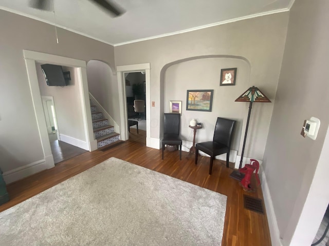 sitting room with crown molding, ceiling fan, and dark wood-type flooring