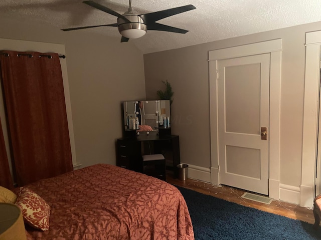 bedroom with dark hardwood / wood-style flooring, a textured ceiling, and ceiling fan