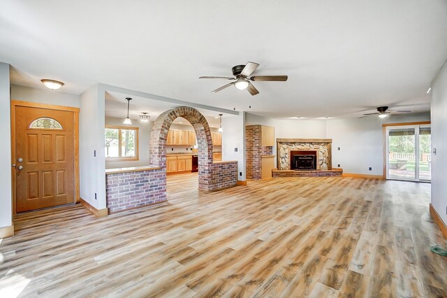 unfurnished living room featuring ceiling fan, a fireplace, and light wood-type flooring