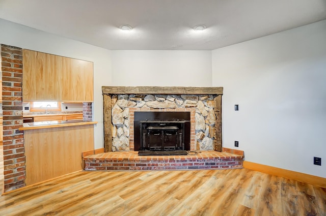 unfurnished living room with hardwood / wood-style flooring, a large fireplace, and sink