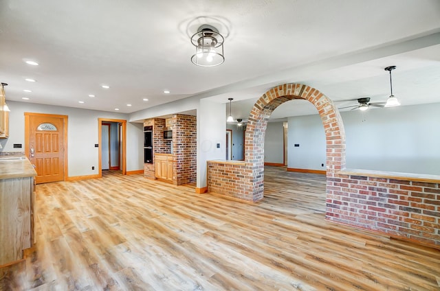 unfurnished living room featuring ceiling fan and light wood-type flooring