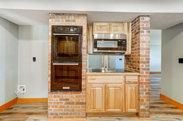 kitchen featuring light brown cabinetry, light wood-type flooring, and black appliances