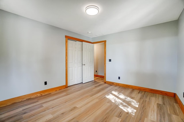 unfurnished bedroom with light wood-type flooring and a closet