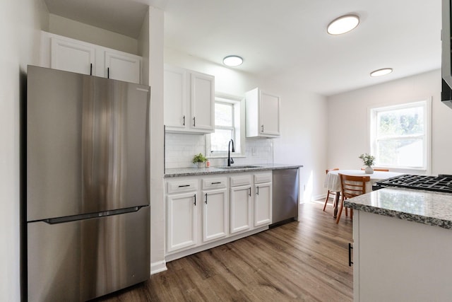 kitchen with white cabinets, light stone countertops, stainless steel appliances, and dark wood-type flooring