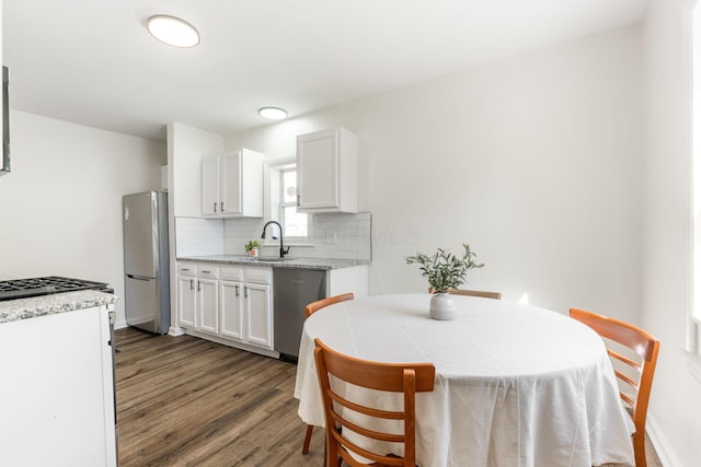 kitchen with white cabinetry, sink, dark wood-type flooring, stainless steel appliances, and light stone counters