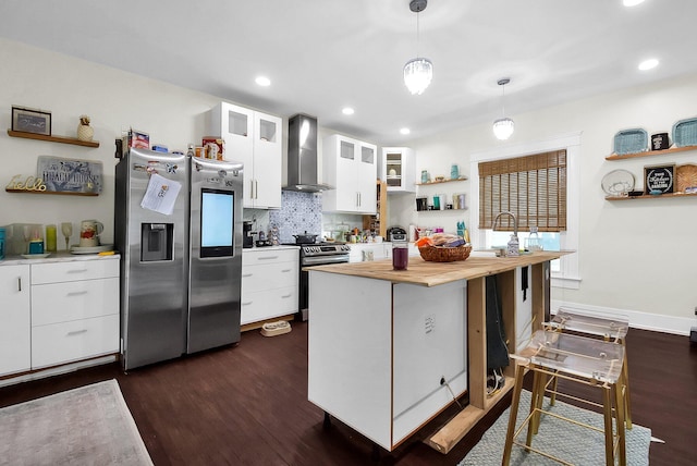 kitchen featuring wall chimney exhaust hood, stainless steel appliances, dark wood-type flooring, decorative light fixtures, and white cabinets