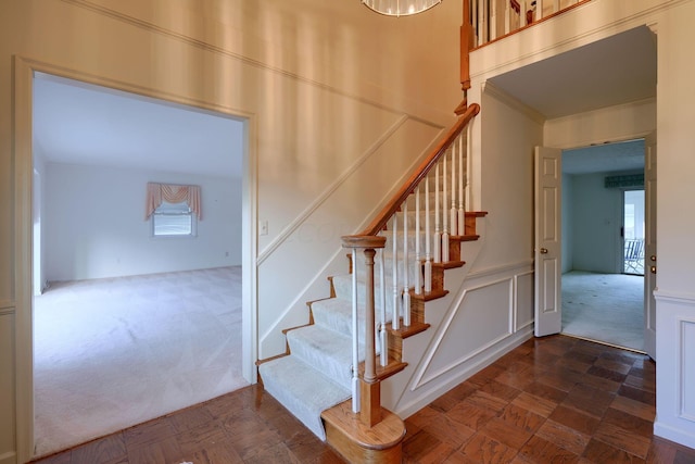 stairway with carpet floors and crown molding