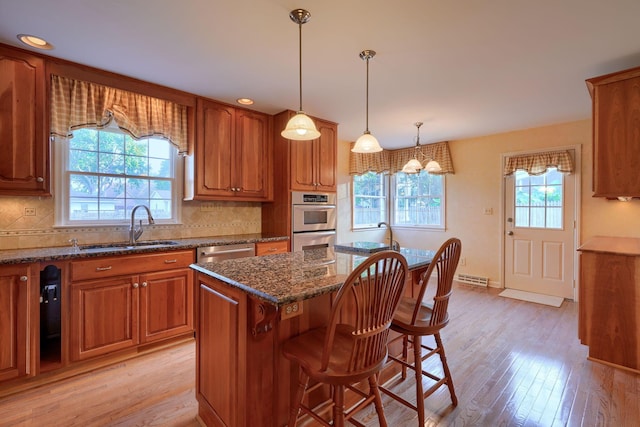 kitchen with a center island, dark stone counters, sink, tasteful backsplash, and light hardwood / wood-style floors