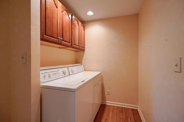 laundry area with cabinets, independent washer and dryer, and light hardwood / wood-style floors