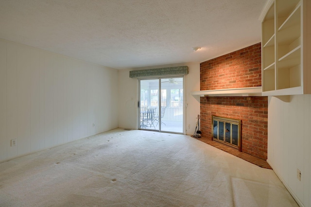 unfurnished living room featuring carpet flooring, a textured ceiling, and a brick fireplace