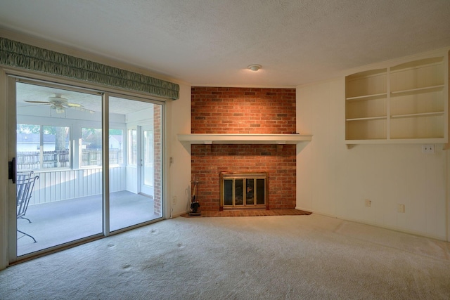 unfurnished living room featuring ceiling fan, carpet, a textured ceiling, and a brick fireplace