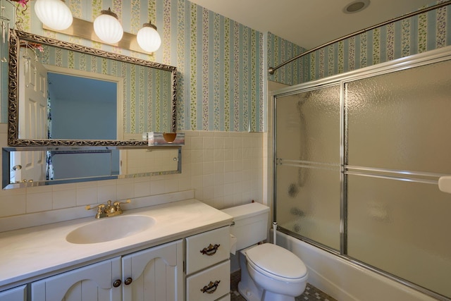 full bathroom with vanity, toilet, combined bath / shower with glass door, and tile walls