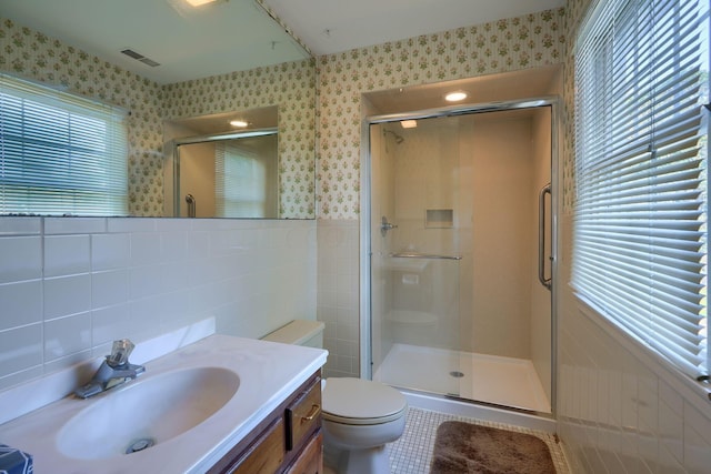 bathroom with vanity, tile patterned flooring, toilet, tile walls, and an enclosed shower