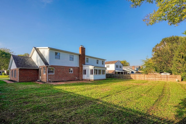 rear view of house featuring a lawn and a sunroom