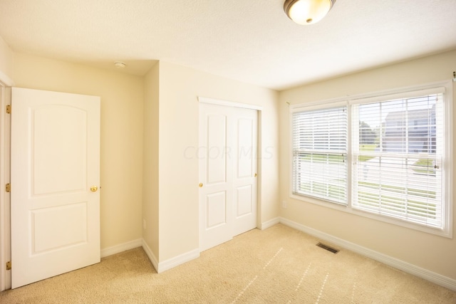 unfurnished bedroom featuring light colored carpet and a closet