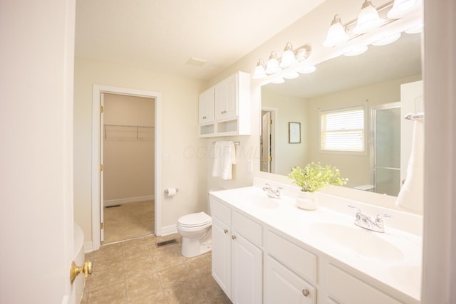 bathroom featuring tile patterned flooring, vanity, a shower with door, and toilet