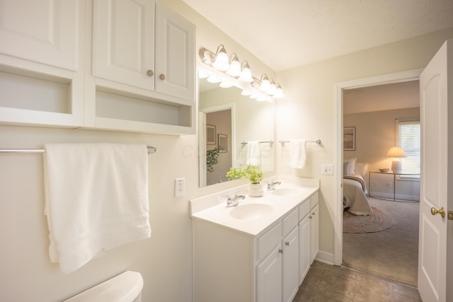 bathroom with tile patterned flooring, vanity, toilet, and a textured ceiling