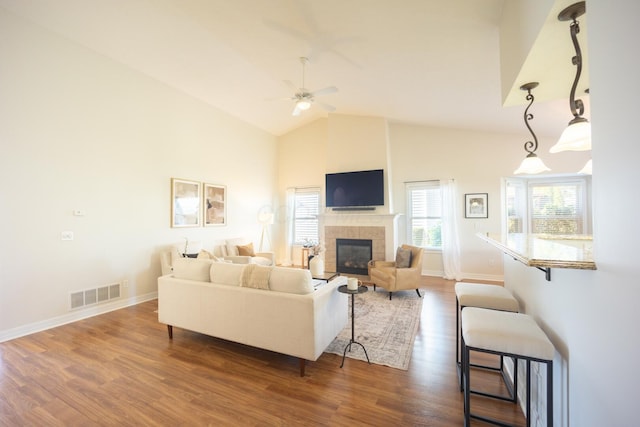 living room with dark hardwood / wood-style floors, ceiling fan, a fireplace, and high vaulted ceiling