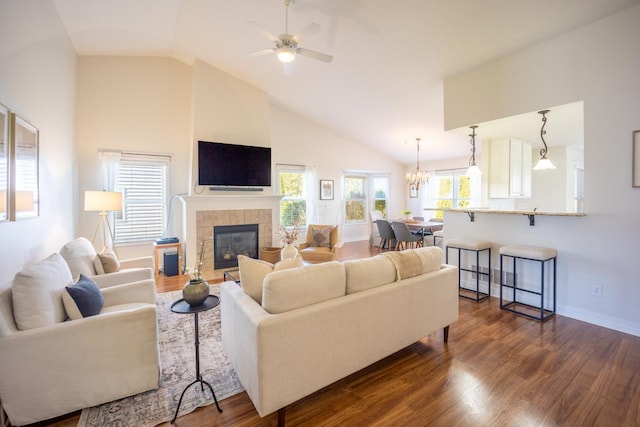 living room featuring a tile fireplace, ceiling fan with notable chandelier, dark hardwood / wood-style floors, and high vaulted ceiling