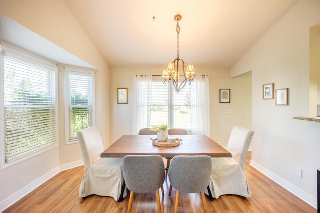 dining space with a chandelier, a healthy amount of sunlight, light hardwood / wood-style floors, and vaulted ceiling