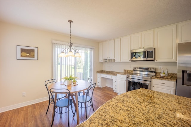 kitchen featuring white cabinets, pendant lighting, wood-type flooring, and appliances with stainless steel finishes