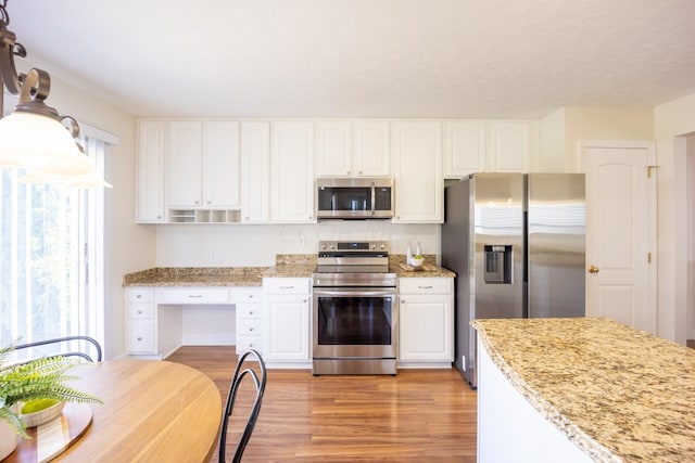 kitchen with white cabinets, light stone countertops, light wood-type flooring, a textured ceiling, and appliances with stainless steel finishes