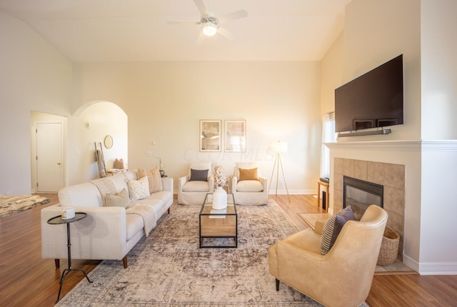 living room featuring a fireplace, hardwood / wood-style floors, high vaulted ceiling, and ceiling fan