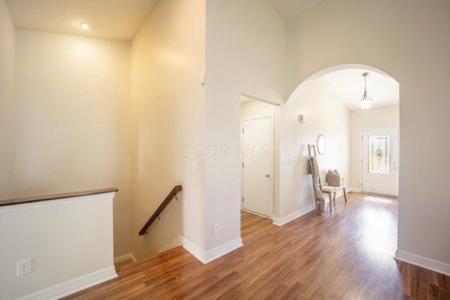 hall with hardwood / wood-style flooring and a towering ceiling