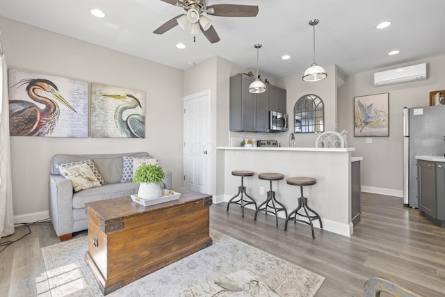 living room featuring a wall mounted air conditioner, hardwood / wood-style flooring, and ceiling fan