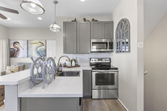 kitchen featuring appliances with stainless steel finishes, dark hardwood / wood-style flooring, backsplash, sink, and gray cabinets