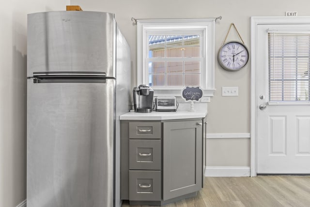 kitchen with gray cabinetry, stainless steel fridge, and light hardwood / wood-style floors